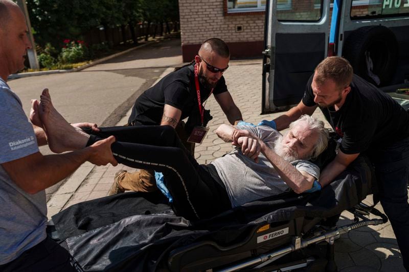 Volunteers on East SOS move en elderly disable man on a stretcher during evacuation in Pokrovsk, Donetsk region, Ukraine, Monday, August 19, 2024. Due to the advance of Russian troops, the war affects more and more new settlements to the west of the Donetsk region. Intensive shelling forced people to leave homes. (AP Photo/Evgeniy Maloletka)