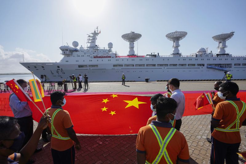 FILE - Sri Lankan port workers hold a Chinese national flag to welcome Chinese research ship Yuan Wang 5, bristling with surveillance equipment, as it arrives in Hambantota International Port in Hambantota, Sri Lanka, on Aug. 16, 2022. (AP Photo/Eranga Jayawardena, File)