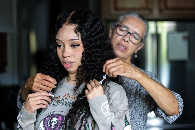 Narvellette , grandmother of Atlanta rapper Anycia, helps the artist put on a necklace at the family home in metro Atlanta. (Arvin Temkar / AJC)