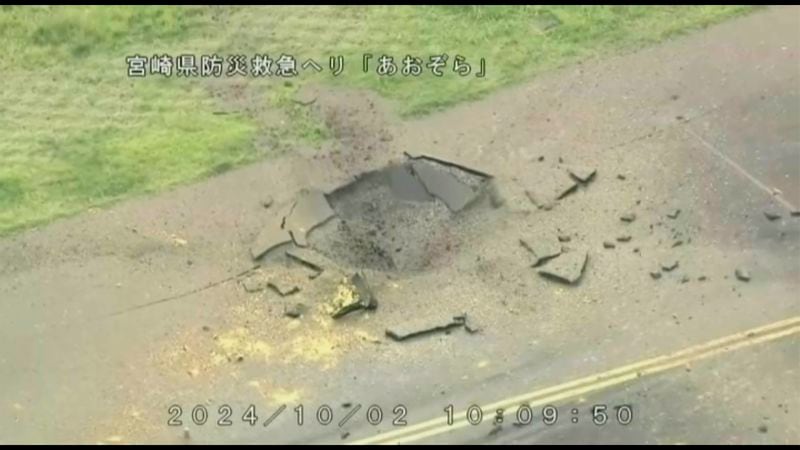 This image from video taken from a helicopter of Miyazaki Prefecture shows part of a damaged taxiway at Miyazaki Airport in southwestern Japan, Wednesday, Oct. 2, 2024, after an explosion was reported. The words at top read: Miyazaki Prefecture Disaster Prevention and Emergency Care Helicopter Aozora. (Miyazaki Prefecture via AP)