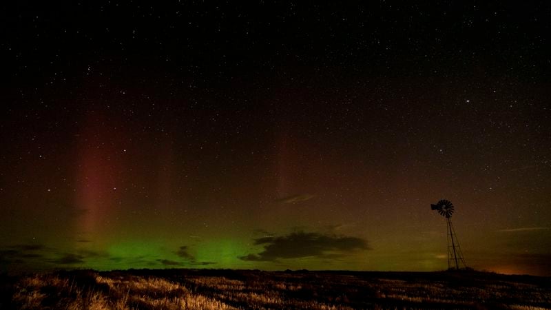 An aurora borealis, also known as the northern lights, is seen in the night sky behind a windmill water pump as lights from a passing vehicle illuminate a field on Tuesday, Sept. 24, 2024, near Washtucna, Wash. (AP Photo/Ted S. Warren)