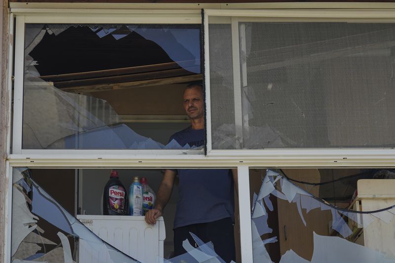 A man looks at a damaged window of a house following an attack from Lebanon, in Acre, north Israel, Sunday, Aug. 25, 2024. (AP Photo/Ariel Schalit)