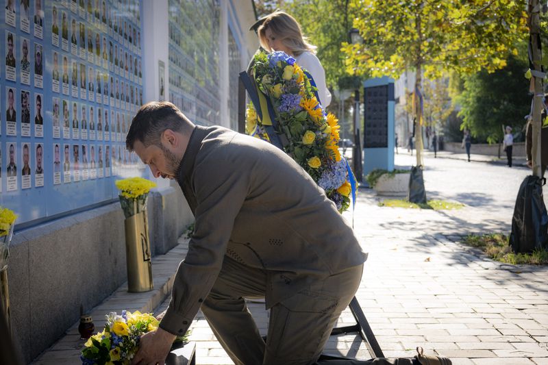 In this photo provided by the Ukrainian Presidential Press Office, Ukrainian President Volodymyr Zelenskyy lays flowers at the Memorial Wall of Fallen Defenders of Ukraine in Russian-Ukrainian War during celebration of the Ukrainian Independence Day in Kyiv, Ukraine, Saturday, Aug. 24, 2024. (Ukrainian Presidential Press Office via AP)