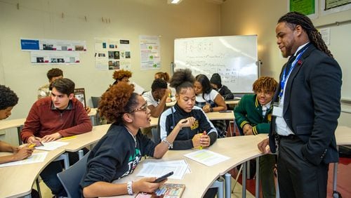 Kelsey Allen, front left, talks with her teacher, Rashad Brown, in their Advanced Placement African American Studies at Maynard Jackson High School on Friday, Feb 17, 2023.  (Jenni Girtman for The Atlanta Journal-Constitution)
