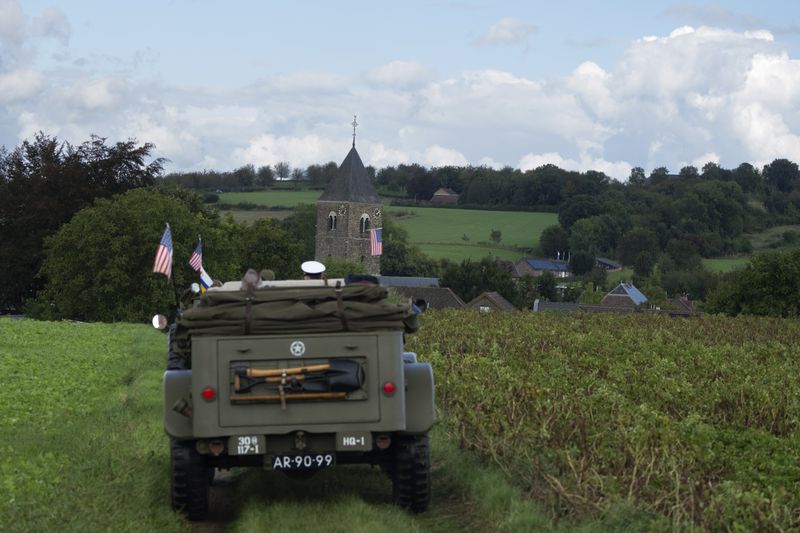 An American flag flies from the bell tower of the church as a convoy of WWII vehicles drives the liberation route during a ceremony marking the 80th anniversary of the liberation of the south of the Netherlands in Mesch, Thursday, Sept. 12, 2024. (AP Photo/Peter Dejong, Pool)