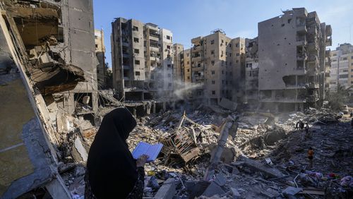 A woman reads the Quran at the site of the assassination of Hezbollah leader Hassan Nasrallah in Beirut's southern suburbs, Sunday, Sept. 29, 2024. (AP Photo/Hassan Ammar)