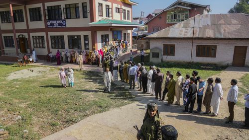 Indian paramilitary soldiers guard as Kashmiris queue up at a polling booth to cast their vote during the final phase of an election to choose a local government in Indian-controlled Kashmir, north of Srinagar, Tuesday, Oct.1, 2024. (AP Photo/Mukhtar Khan)