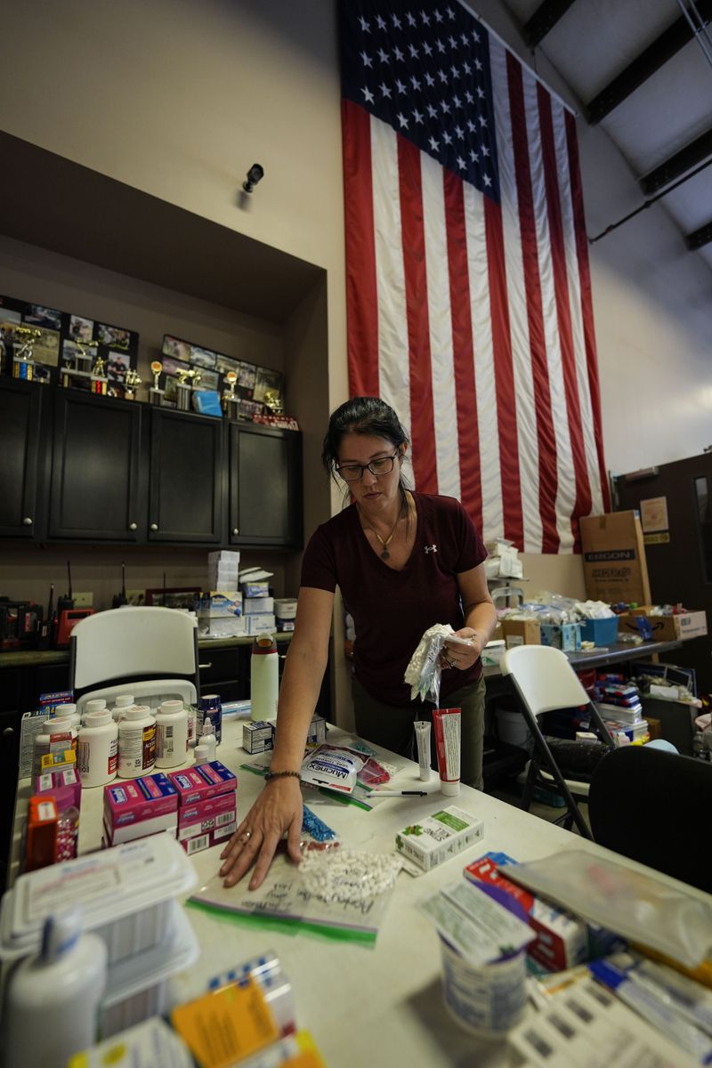 A volunteer gathers food for families at the volunteer fire station in the aftermath of Hurricane Helene, Thursday, Oct. 3, 2024, in Pensacola, N.C. (AP Photo/Mike Stewart)