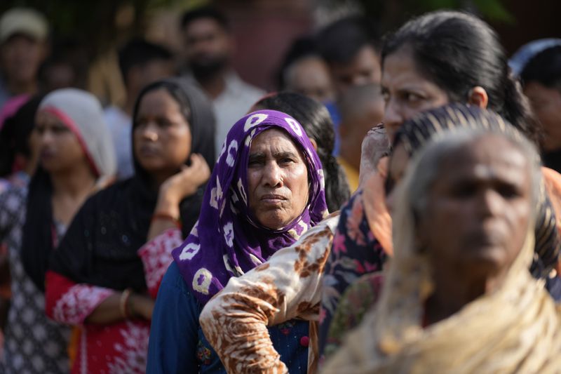 People queue up to cast their vote at a polling booth during the final phase of an election to choose a local government in Indian-controlled Kashmir, in Jammu, India, Tuesday, Oct.1, 2024. (AP Photos/Channi Anand)