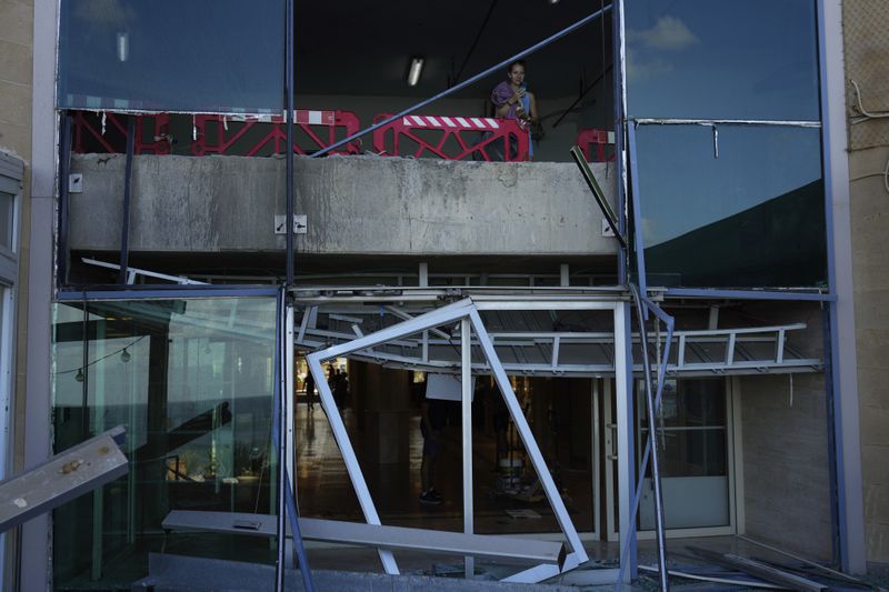 A woman looks from a damaged building that was hit during Iran's missile attack in Tel Aviv, Israel, Wednesday, Oct. 2, 2024. (AP Photo/Ariel Schalit)