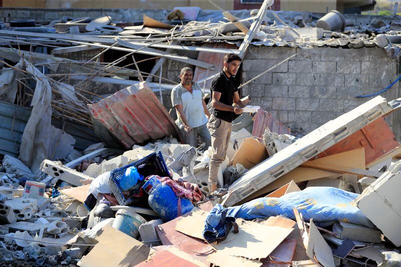 Men stand on the rubble of a building hit in an Israeli airstrike in the southern village of Akbieh, Lebanon, Tuesday, Sept. 24, 2024. (AP Photo/Mohammed Zaatari)