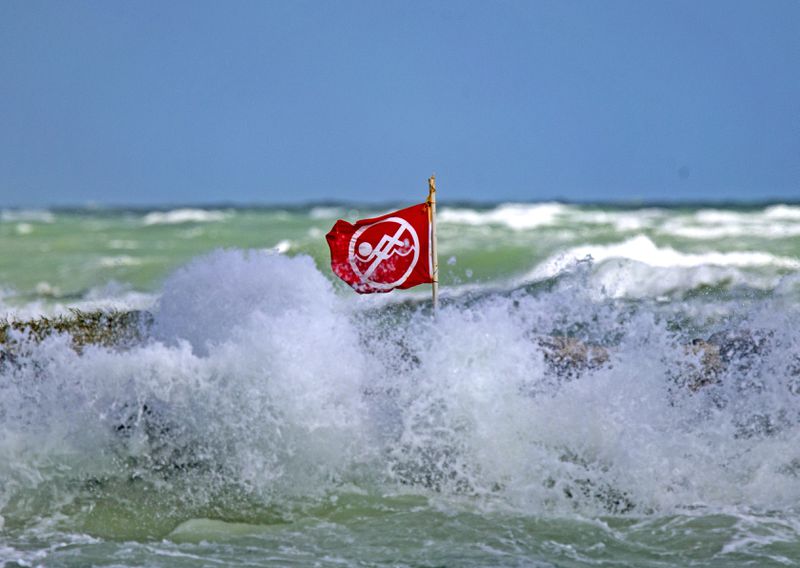 FILE - A no swimming flag is visible as waves crash against the rocks at Haulover Beach Park, November 18, 2020, in Miami Beach, Florida. About 100 people drown from rip currents along U.S. beaches each year, according to the U.S. Lifesaving Association, and more than 80 percent of beach rescues annually involve rip currents. (David Santiago/Miami Herald via AP, File)