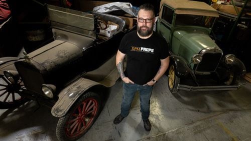 Thomas Kerns poses for a photo in front of a Ford Model T and a 1928 Ford Model A in his Atlanta prop house on July 25. Kerns' prop house employed five crew members, but he had to lay all of them off about three months ago. (Steve Schaefer/steve.schaefer@ajc.com)