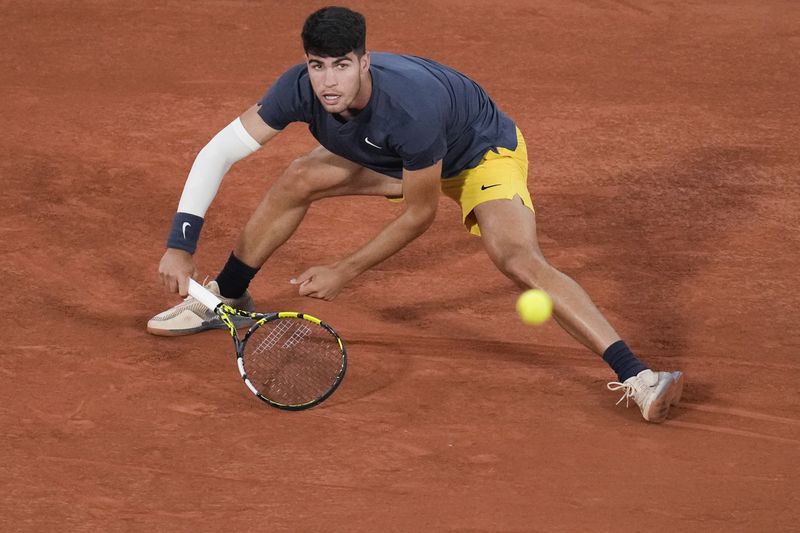 Spain's Carlos Alcaraz slides to play shot against Jeffrey John Wolf of the U.S. during their first round match of the French Open tennis tournament at the Roland Garros stadium in Paris, Sunday, May 26, 2024. (AP Photo/Christophe Ena)