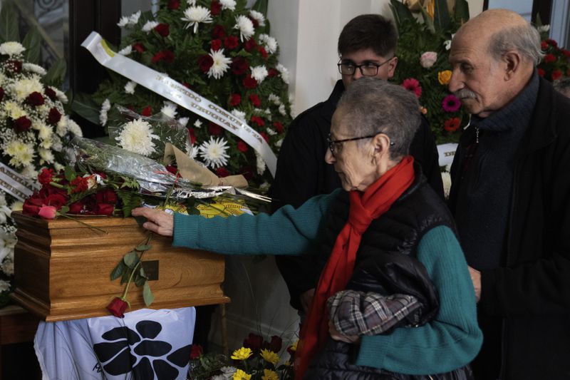 A woman places a red rose on the coffin that contains the remains of Amelia Sanjurjo sits inside a hearse during her funeral service at the University of the Republic, in Montevideo, Uruguay, Thursday, June 6, 2024. The Uruguayan Prosecutor’s Office confirmed that the human remains found in June 2023 at the 14th Battalion of the Uruguayan Army belong to Sanjurjo, a victim of the 1973-1985 dictatorship who was 41 years old and pregnant at the time of her disappearance. (AP Photo/Matilde Campodonico)
