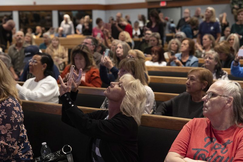 Attendees of a Comeback California Tour event at Revival Fellowship photograph information from a slideshow, Saturday, Sept. 21, 2024, in Menifee, Calif. (AP Photo/Zoë Meyers)