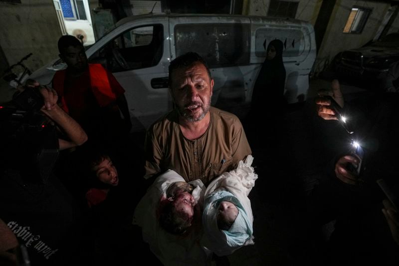 Osama al-Taweel holds the bodies of his grandchildren who were killed during an Israel airstrike in the Gaza Strip, as he arrives at the hospital morgue in Deir al Balah, Thursday, Aug. 29, 2024. (AP Photo/Abdel Kareem Hana)