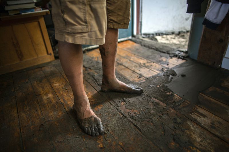 A resident, with muddy feet, stands in his damaged home following flooding caused by the remnants of Hurricane Beryl, Thursday, July 11, 2024, in Plainfield, Vt. (AP Photo/Dmitry Belyakov)