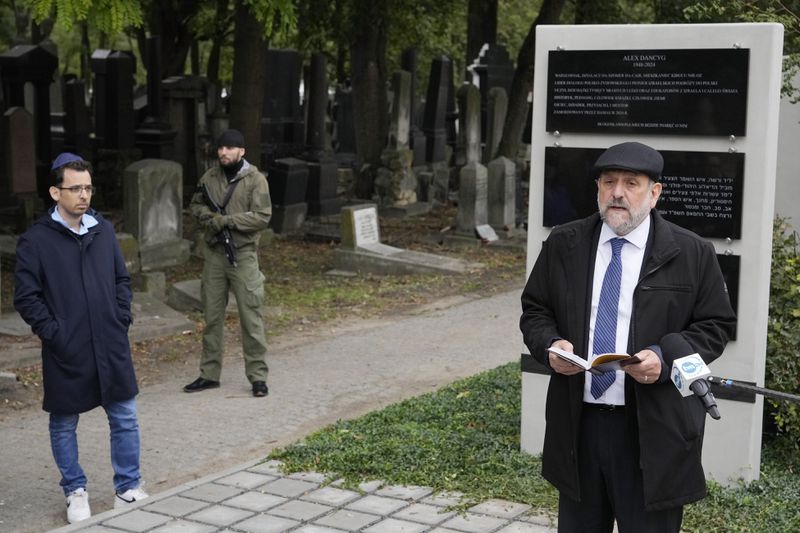 Yuval Danzig, left, the son of a Polish-Israeli man kidnapped and killed by Hamas, and Poland's chief rabbi Michael Schudrich unveil a plaque honoring his father, Alex Dancyg, in the Jewish cemetery in Warsaw, Poland, on Monday, Oct. 7, 2024. (AP Photo/Czarek Sokolowski)