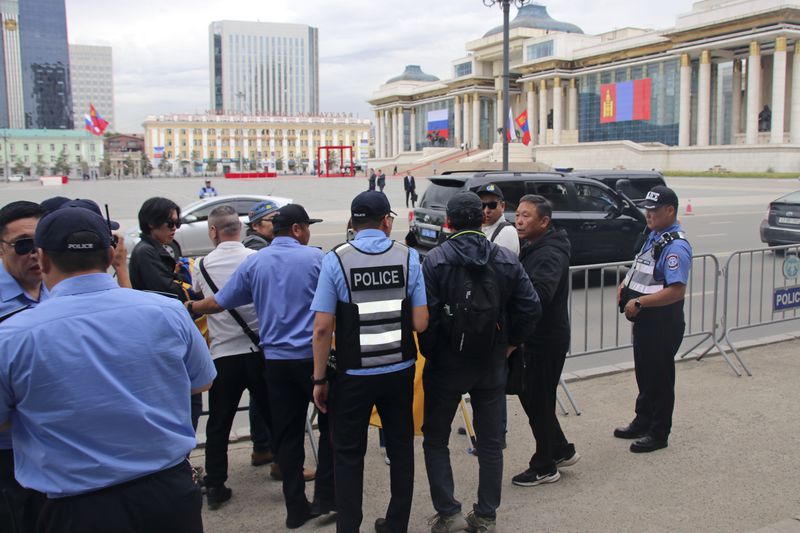 Police and security officers prevent members of the "No War" group from holding up a Ukrainian flag during the visit of Russian President Vladimir Putin in Ulaanbaatar, Mongolia, Tuesday, Sept. 3, 2024. (AP Photo/Ganbat Namjilsangarav)