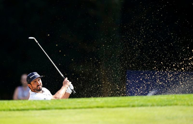 Mark Hubbard of the United States chips out of a bunker on the 1st during day two of the 2024 BMW PGA Championship at Wentworth Golf Club in Virginia Water, England, Friday Sept. 20, 2024. (Zac Goodwin/PA via AP)