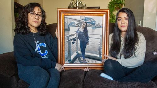 Jessica Aguilar, right, and her sister Jennifer sit by a photograph of their mother in their Roswell home on Sunday, January 23, 2022. (Steve Schaefer for The Atlanta Journal-Constitution)