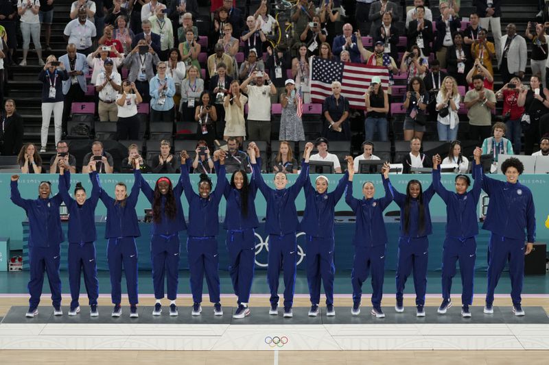 The United States team celebrates their gold medal win at Bercy Arena at the 2024 Summer Olympics, Sunday, Aug. 11, 2024, in Paris, France. (AP Photo/Michael Conroy)