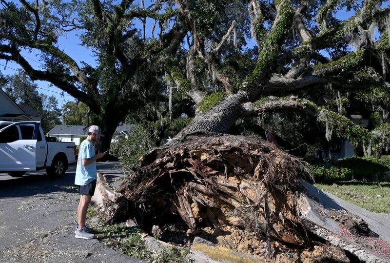 Valdosta State University student Nealy Hiers takes a picture of a fallen tree caused by Hurricane Helene. The storm ripped through the state, killing at least 25 Georgians. (Hyosub Shin/AJC)