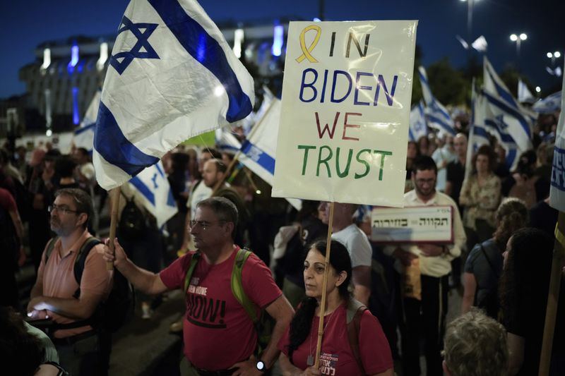 People wave Israeli flags and signs during a protest against Israeli Prime Minister Benjamin Netanyahu's government and demanding elections outside of the Knesset, Israel's parliament, in Jerusalem, Tuesday, June 18, 2024. (AP Photo/Leo Correa)