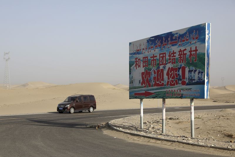 FILE - A car drives through a desert where a signboard which reads "Welcome to the Hotan Unity New Village" is seen on display in Hotan, in western China's Xinjiang region on Sept. 21, 2018. Authorities in China's western Xinjiang region have been systematically replacing the names of villages inhabited by Uyghurs and other ethnic minorities to reflect the ruling Communist Party's ideology, as part of an attack on their cultural identity, according to a report released Wednesday, June 19, 2024 by Human Rights Watch. (AP Photo/Andy Wong, File)