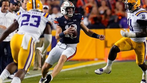 Auburn quarterback Bo Nix (10) scrambles between LSU defensive end Ali Gaye (11) and linebacker Micah Baskerville (23) in the first half of an NCAA college football game in Baton Rouge, La., Saturday, Oct. 2, 2021. (AP Photo/Gerald Herbert)