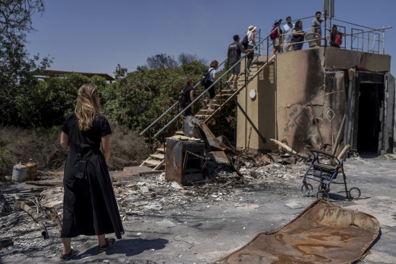 A group of Israelis on an educational tour visit a house that was torched by Hamas militants on the Oct. 7 attack on Israel in Kibbutz Nir Oz, on Friday, June 21, 2024. A new kind of tourism has emerged in Israel in the months since Hamas’ Oct. 7 attack. For celebrities, politicians, influencers and others, no trip is complete without a somber visit to the devastated south that absorbed the brunt of the assault near the border with Gaza. (AP Photo/Ohad Zwigenberg)