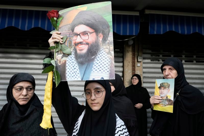 Hezbollah supporters carry pictures of Hezbollah commander Ibrahim Akil, right, and Hezbollah leader Hassan Nasrallah, centre, during Akil's funeral procession in Beirut's southern suburb, Sunday, Sept. 22, 2024. (AP Photo/Bilal Hussein)