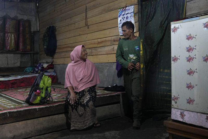 Forest ranger Rosita, left, talks with her husband Muhammad Saleh, a former poacher, before leaving for a forest patrol, at their house in Damaran Baru, Aceh province, Indonesia, Tuesday, May 7, 2024. It took years, but eventually Saleh felt the message of his wife. He stopped poaching and cutting down trees and began joining his wife on patrols of the forest. (AP Photo/Dita Alangkara)