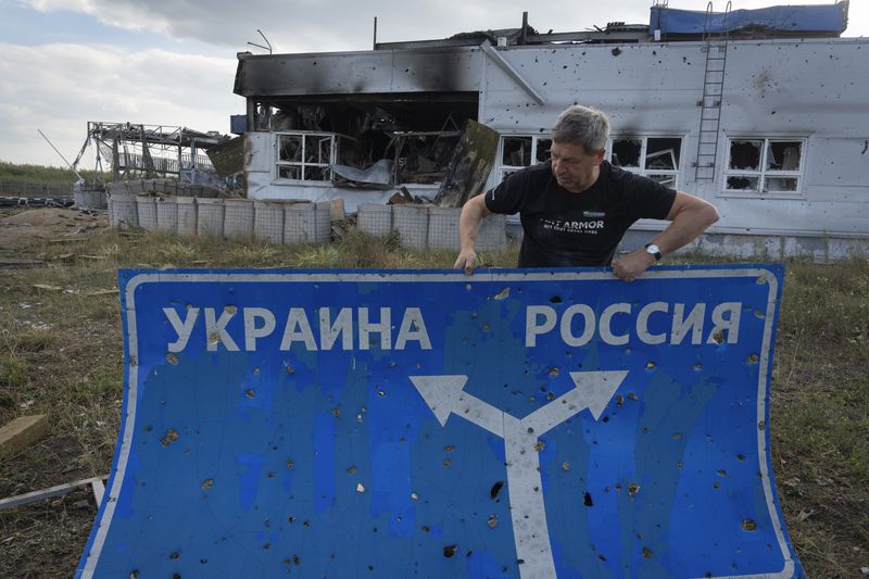 FILE - Ukrainian historian Yuri Savchuk carries a road sign in Sudzha, Russia, on Aug. 16, 2024. This image was approved by the Ukrainian Defense Ministry before publication. (AP Photo, File)