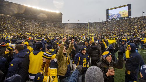 Michigan fans celebrate on the Michigan Stadium field after an NCAA college football game against Ohio State in Ann Arbor, Mich., Saturday, Nov. 27, 2021. Michigan won 42-27. (AP Photo/Tony Ding)