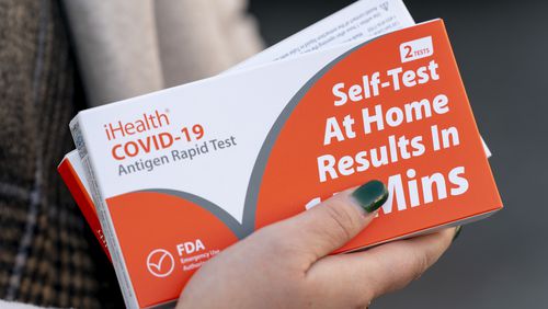 FILE - A woman holds two boxes of at-home Covid-19 test kits in Washington, Dec. 22, 2021. (AP Photo/Andrew Harnik, File)