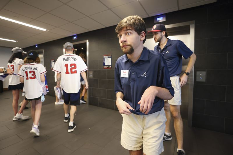 Atlanta Braves greeter Wilson Barron helps fans find their seats in an elevator lobby before a Braves game. (Jason Getz / AJC)

