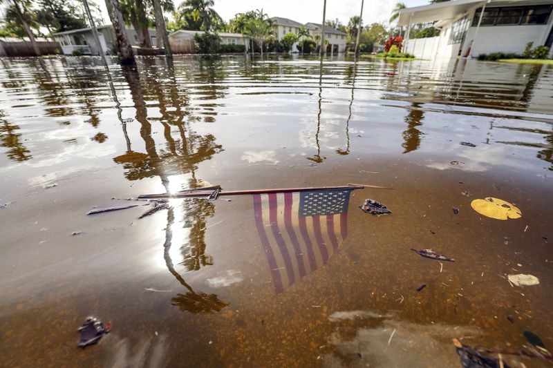 An American flag sits in the floodwaters from Hurricane Helene in the Shore Acres neighborhood Friday, Sept. 27, 2024, in St. Petersburg, Fla. (AP Photo/Mike Carlson)