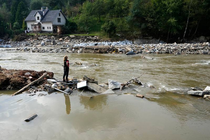 A woman stands by a river as residents return to clean up after recent floods near Pisecna, Czech Republic, Thursday, Sept. 19, 2024. (AP Photo/Petr David Josek)