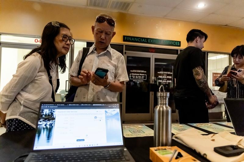 Members of the Las Vegas Asian community scan a QR code taking them to voter information translated into Chinese during the annual Dragon Boat Festival in Las Vegas on Wednesday, June 5, 2024. (Photo by Christopher Lomahquahu/News21)