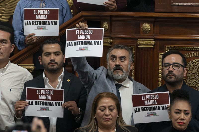 Mexico City lawmakers in favor of judicial reform hold signs that reads in Spanish ¨The people rule. Reform now!¨ at the city Congress in Mexico City, Thursday, Sept. 12, 2024. (AP Photo/Felix Marquez)