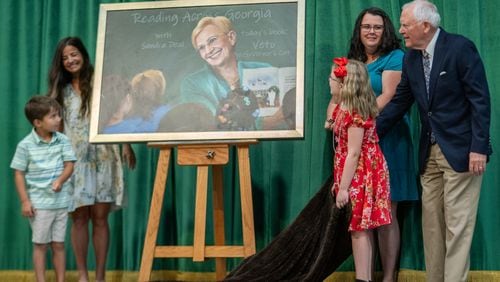 Former Gov. Nathan Deal, right, unveils a portrait of his late wife Sandra Deal with the help of teachers and students at the school named for her. Family, friends and community members gather for the dedication ceremony of Sandra Dunagan Deal Elementary School. Monday, August 26, 2024 (Ben Hendren for the Atlanta Journal-Constituion)