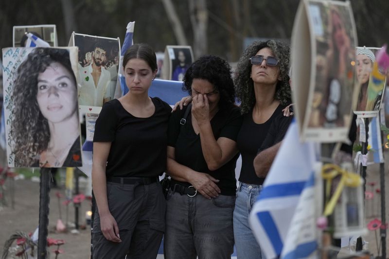 People react during a ceremony at the site of the Nova music festival, where hundreds of revelers were killed and abducted by Hamas and taken into Gaza, on the one-year anniversary of the attack, near Kibbutz Reim, southern Israel, Monday, Oct. 7, 2024. (AP Photo/Ariel Schalit)