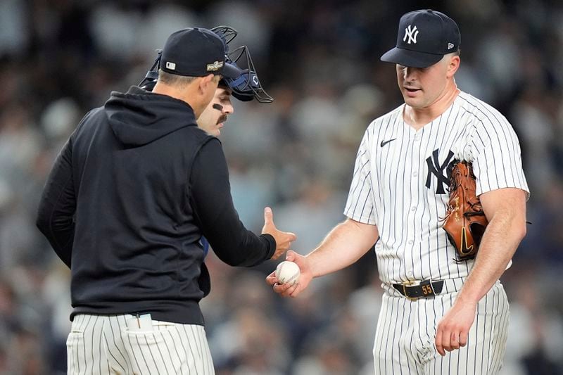 New York Yankees pitcher Carlos Rodón hands the ball to manager Aaron Boone as he leaves the game during the fourth inning of Game 2 of the American League baseball playoff series against the Kansas City Royals, Monday, Oct. 7, 2024, in New York. (AP Photo/Frank Franklin II)