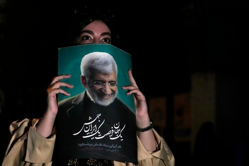 A supporter of Saeed Jalili, a candidate for the presidential election, holds up his poster during a campaign gathering in Tehran, Iran, Wednesday, June 26, 2024. (AP Photo/Vahid Salemi)