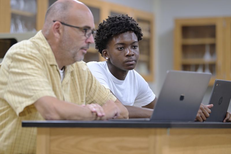 History teacher Matt Brophy, left, works with Flerentin “Flex” Jean-Baptiste, 16, of Medford, Mass., on making up late assignments during summer school at Medford High School, Friday, Aug. 2, 2024, in Medford. (AP Photo/Josh Reynolds)