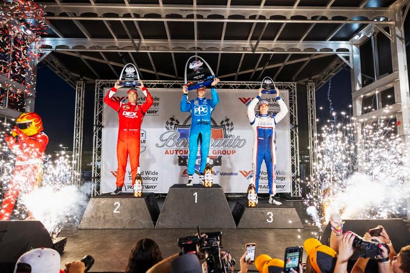 From left, Scott McLaughlin, Josef Newgarden, and Marcus Armstrong hold their trophies in the air while confetti erupts on Saturday, Aug. 17, 2024, at World Wide Technology Raceway in Madison, Ill. (Zachary Linhares/St. Louis Post-Dispatch via AP)