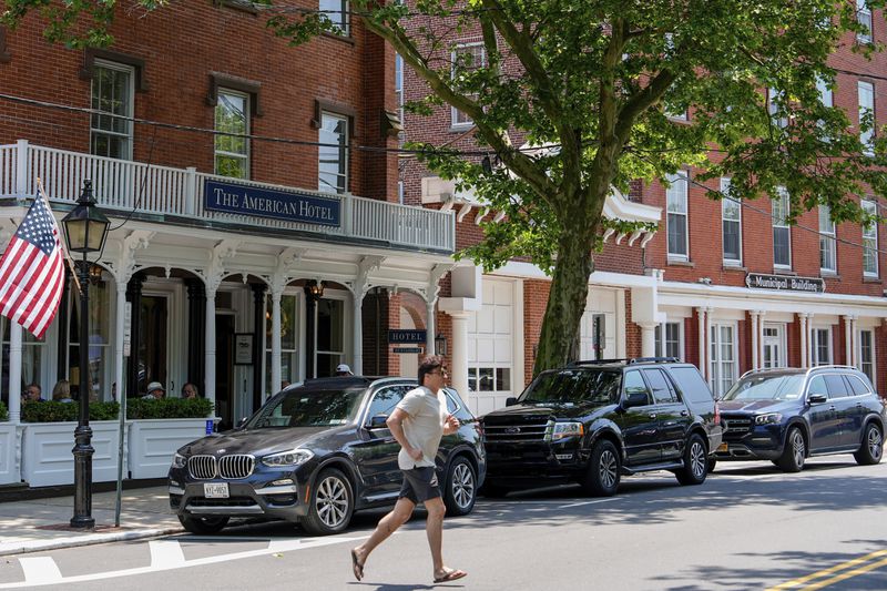 A man crosses in front of Sag Harbor Village Hall and The American Hotel, Tuesday, June 18, 2024, in Sag Harbor, N.Y. (AP Photo/Julia Nikhinson)