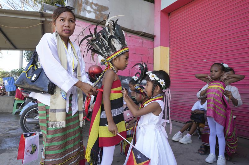 A mother helps her son to wear a traditional outfit to welcome Pope Francis' visit in Dili, East Timor Monday, Sept. 9, 2024. (AP Photo/Firdia Lisnawati)